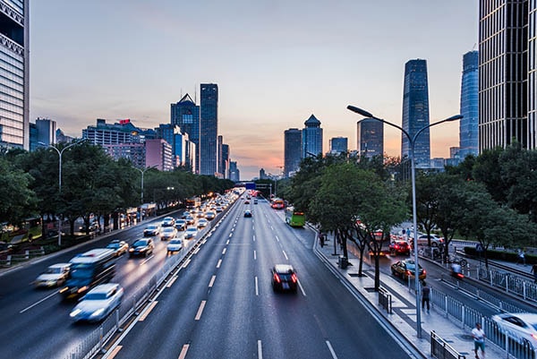 A highway in the middle of a city with lots of cars in motion.