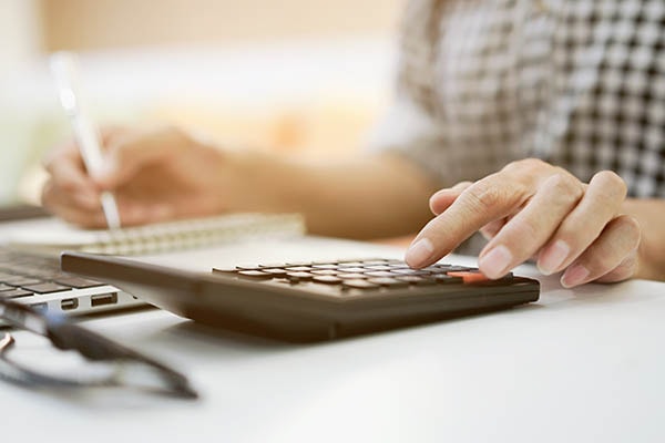 A person writing something down while calculating.