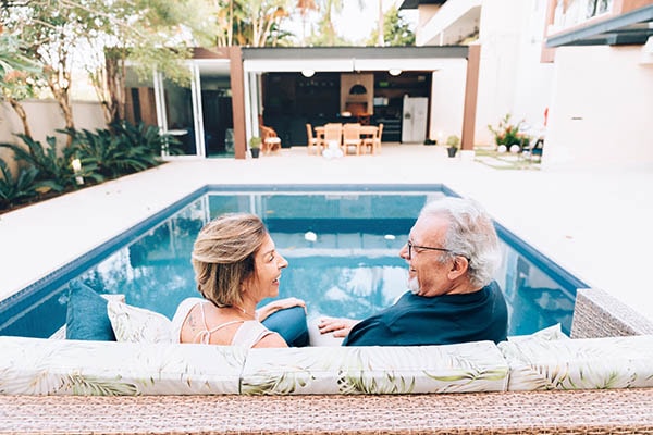 A couple sitting next to each other while overlooking a pool.