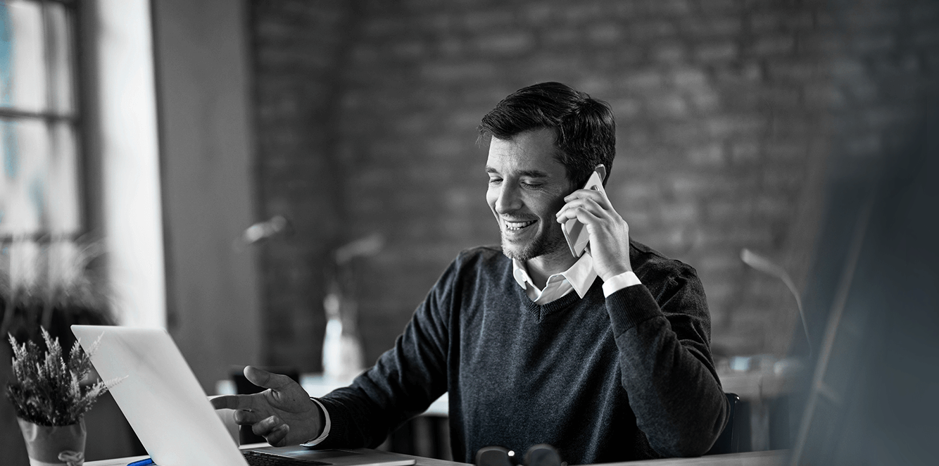 A person talking on their phone while sitting at a computer